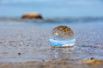 Beach and sea reflected in a sphere lying  in the water