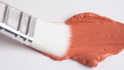 Wall Mural - Texture of orange clay mask. Swatch of red clay mask. Makeup brush applying orange facial mask on white background.