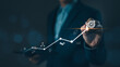 © Supatman - Business startup and investment goals concept. Businessman is touching the growing business graph. Planning and starting corporate business start up, Rocket soars with speed to hit the growth target.