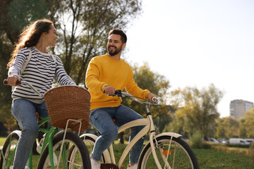 Poster - Beautiful couple riding bicycles in park, space for text