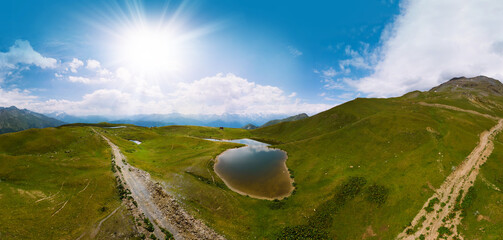 Wall Mural - Aerial view at the Koruldi lakes. Green hills, high mountain pastures. Summer day. in the background are the snowy peaks of the Caucasus Mountains. High resolution panorama