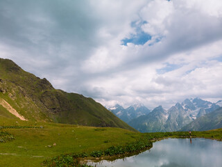 Wall Mural - Aerial view at the Koruldi lakes in Caucasus mountains, Mestia, Svaneti region, Georgia. Summer day, green hills, mountain pasture for livestock, snow mountain peaks.