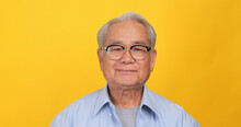 Close Up, Portrait Of Older Man Smiling And Looking At The Camera. Isolated On Yellow Background In The Studio.
