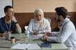 © Seventyfour - Muslim woman doctor in beige headscarf carefully listening to male colleague and making notes while sitting at desk in conference room