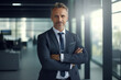 © FutureStock - Portrait of a male team leader in his 40s smiling with crossed arms in the office, radiating leadership and vision.