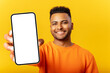 © Vadim Pastuh - Young indian man demonstrates smartphone with blank screen and rejoicing, guy likes mobile app, looking and smiling at the camera, feels satisfied, isolated