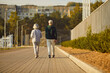 © Studio Romantic - Senior retired couple wearing sportswear walking along a path in the park having sport workout. Elderly men and women exercising outdoors. Workout in nature and healthy lifestyle concept.