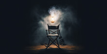 A Director's Chair Inside A Light Bulb Surrounded By Smoke