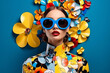Portrait of a beautiful young woman in stylish sunglasses on blue background with decorative flowers. Beauty and fashion concept.