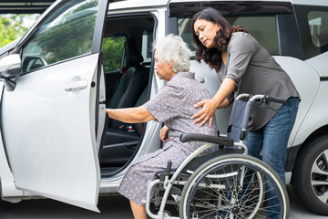 Caregiver help and support asian elderly woman sitting on wheelchair prepare get to her car to travel in holiday.