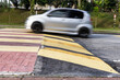 © ThamKC - Car slowing down at speed bump or road hump painted in yellow and black stripe. Motion blur intended.