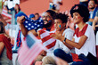 © Drazen - Happy black family cheering for USA during sports match at stadium.