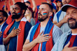 © Drazen - Group of sports fans with hand on heart singing national anthem during championship at stadium.