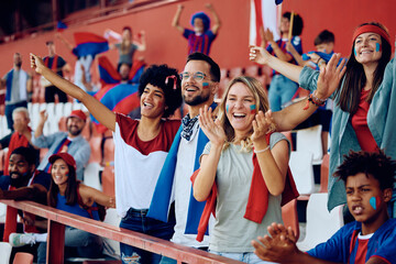 Wall Mural - Group of happy friends cheering from stadium stands during sports match.