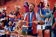 © Drazen - Passionate sports fan playing drums during match at stadium.