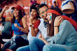 © Drazen - Young happy people celebrating victory of their favorite team while watching sports game at stadium.