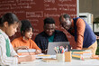 © Mediaphotos - Smiling Black teacher helping students working on group project together and using laptop