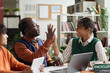 Portrait of smiling African American girl high five with senior professor while working on project in school classroom