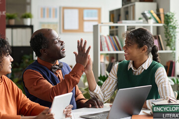 Wall Mural - Portrait of smiling African American girl high five with senior professor while working on project in school classroom