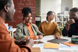 © Mediaphotos - Portrait of smiling curly haired girl enjoying discussion on group project with students in college copy space