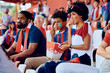 © Drazen - Black family eating popcorn while watching sports game at stadium.