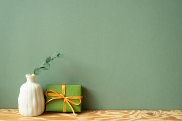 Wall Mural - Green gift box and vase of eucalyptus on wooden table. green wall background