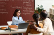 © Mediaphotos - Portrait of young woman as teacher or student advisor shaking hands with parent during meeting in class