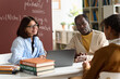 © Mediaphotos - Portrait of smiling young woman as teacher or student advisor talking to young girl during meeting in class