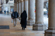 A nun walking among the pillars in the grand old city