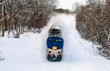Amtrak passenger train in deep snow banking slightly through a high speed turn in Michigan