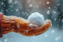 Gloved Hand Holding A Snowball On A Snowing Day