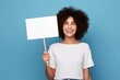 © Alexandra Selina - Young happy woman holding white mockup sign or placard on blue background