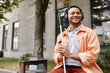 © LIGHTFIELD STUDIOS - jolly indian man with blindness in headphones with walking stick enjoying music while outside