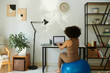 © DragonImages - Woman sitting on fitness ball when working on laptop at home, view from behind