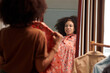 © DragonImages - Woman trying on clothes in front of mirror when getting ready for work in the morning