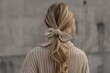 blonde woman from the back with a ponytail and a bow wearing cashmere sweater, neutral colors close up