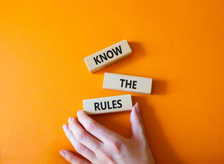 Sticker - Know the rules symbol. Wooden blocks with words Know the rules. Beautiful orange background. Businessman hand. Business and Know the rules concept. Copy space.