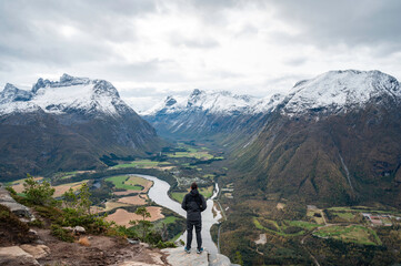 Traveler with his back turned, hands open, enjoying a mountain landscape in the Norwegian fjords of the city of Andalsnes, Norway.