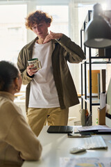 Aufkleber - Young businessman with cup of coffee standing in front of female colleague at break in office and explaining something
