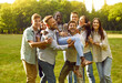 Group of friends having fun outdoors. Multiracial group of cheerful best friends having fun together enjoying summer day in park. Men and women lift up their dark-skinned girlfriend. Lifestyle concept