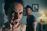 Fototapeta  - Angry young adult Caucasian woman yelling versus her husband at home living room, Young couple arguing and fighting. Domestic violence, emotional abuse scene of woman and man screaming at each other