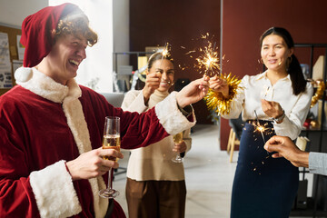 Poster - Young cheerful office managers with burning sparklers and flutes of champagne enjoying Christmas party after working day
