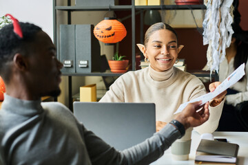 Leinwandbilder - Two young African American office managers or analysts in Halloween costumes looking at financial document and analyzing data