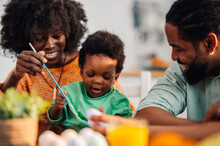Happy African American Family Of Three Painting Easter Eggs Together