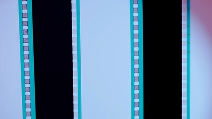 Two vertical film strips on a white and pink gradient background, close up. 35mm film slide frame. Long, retro film strip frame. Copy space.