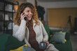 © Miljan Živković - woman with curly hair at home use mobile phone smartphone have a call