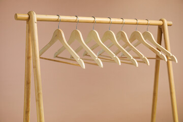 Sticker - Empty clothes hangers on wooden rack against light brown background