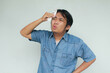 Close up portrait of Asian young man in blue shirt with het gestures in the summer and wiping sweat with tissue.