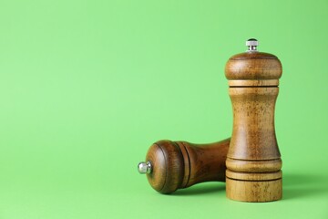 Wooden salt and pepper shakers on green background, closeup. Space for text