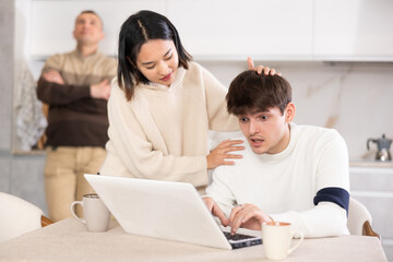 Wall Mural - Girl persuades a young guy to stop playing computer games. Upset father in the background